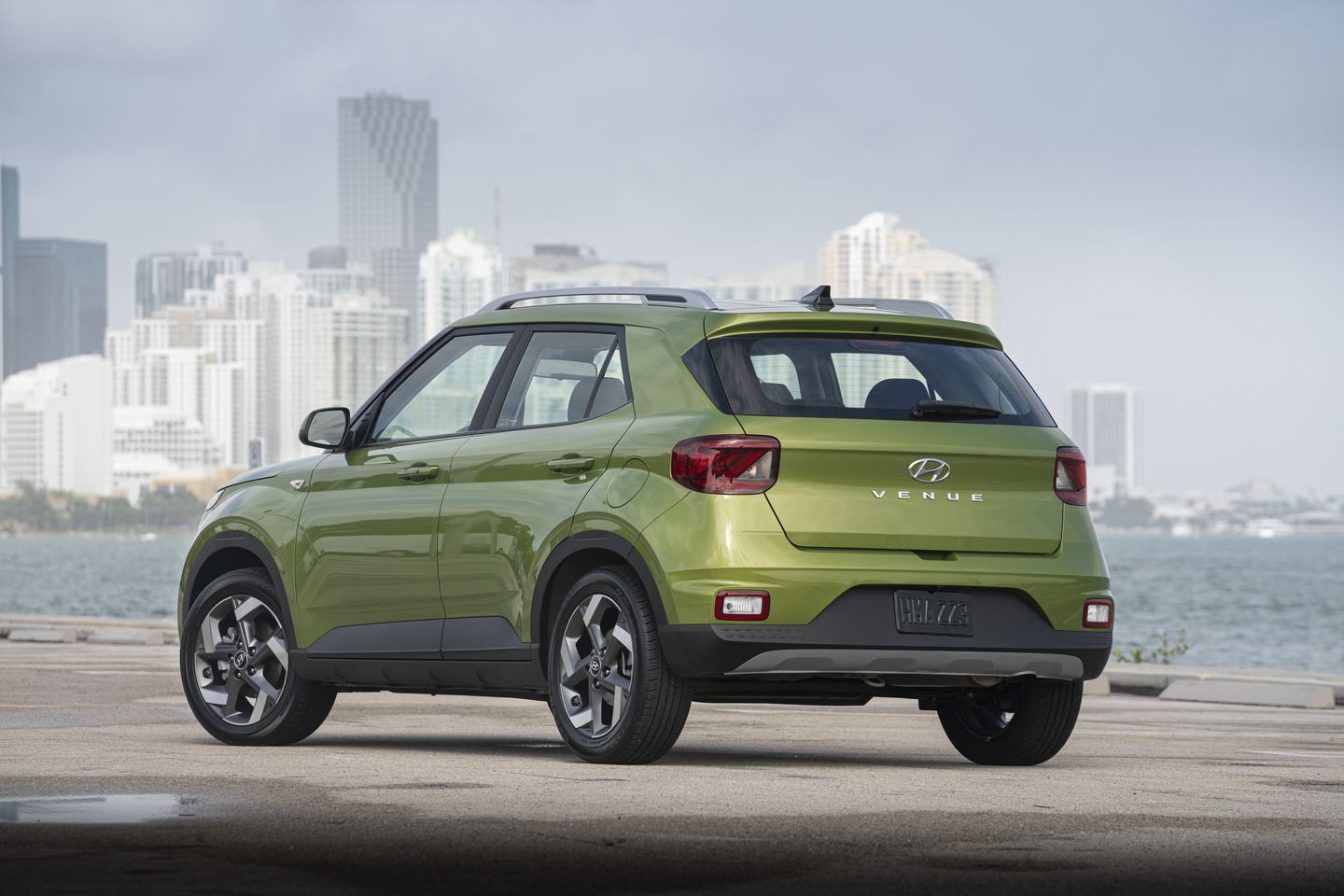 2026 Hyundai Venue - rear three-quarter view of a green 2026 Hyundai Venue parked near the water with a city skyline in the background - Woodstock Hyundai - New car dealership in Woodstock, Ontario