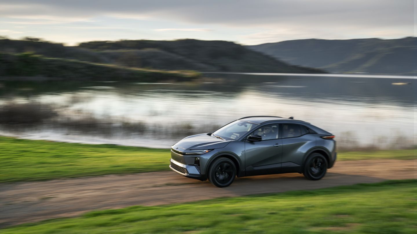 2026 Toyota C-HR - side view of a grey 2026 Toyota C-HR driving along a dirt path next to a body of water - Goderich Toyota - Toyota New car dealership in Goderich, Ontario