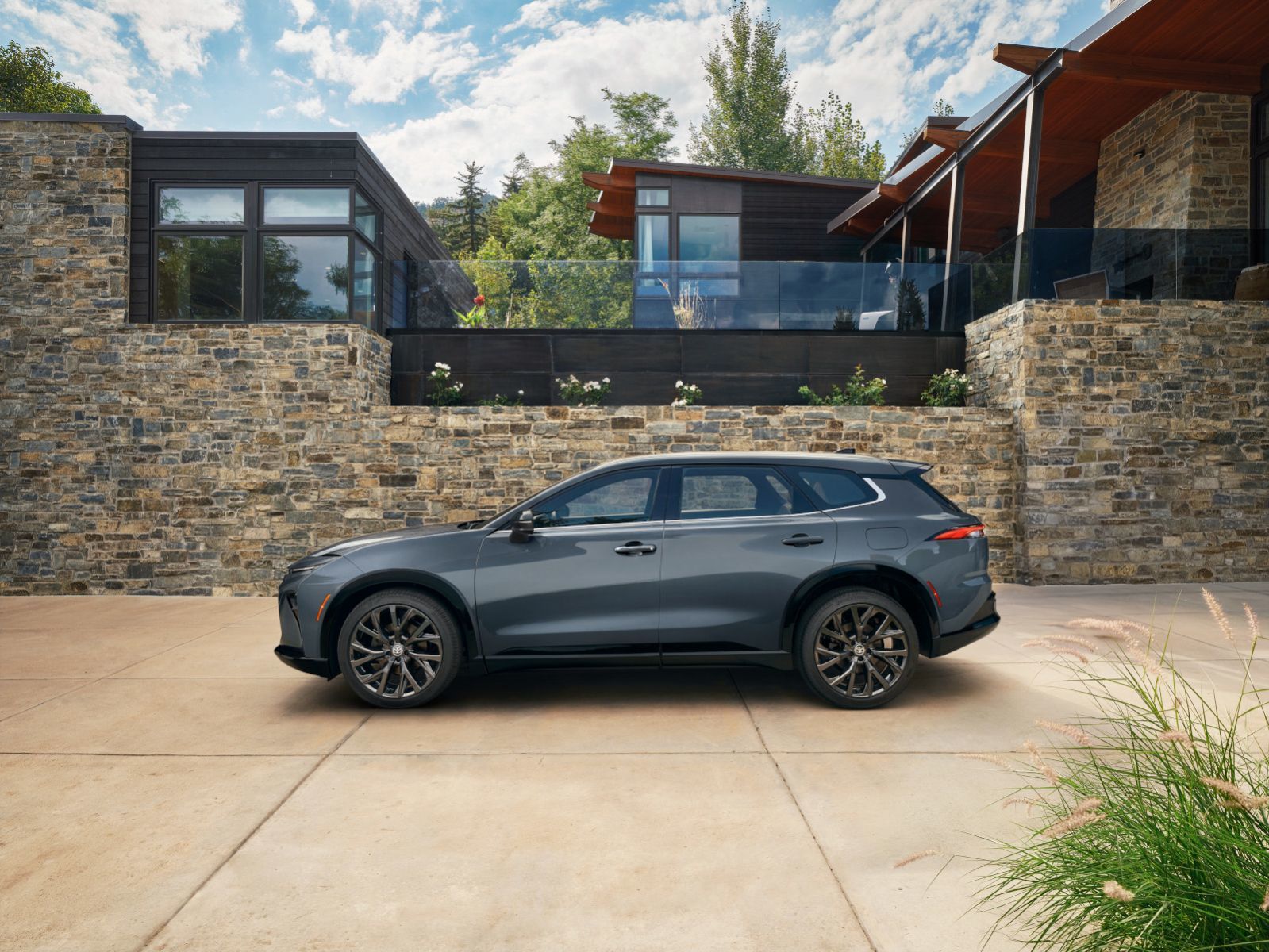 2026 Toyota Crown Signia - a gray 2026 Toyota Crown Signia parked on a concrete driveway in front of a modern stone and wood building - Oakville Toyota - Toyota new car dealership in Oakville, Ontario