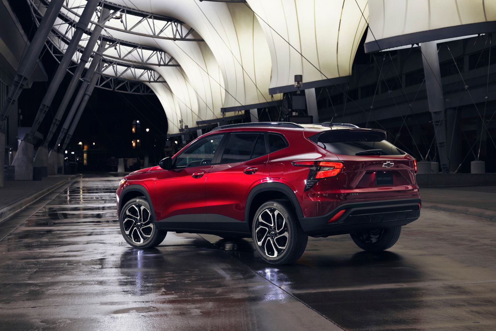 2026 Chevrolet Trax - Rear 3/4 view of a red Chevrolet Trax parked on a wet surface at night under an illuminated canopy structure - Applewood Chevrolet, Buick, GMC - New car dealership in Mississauga, Ontario