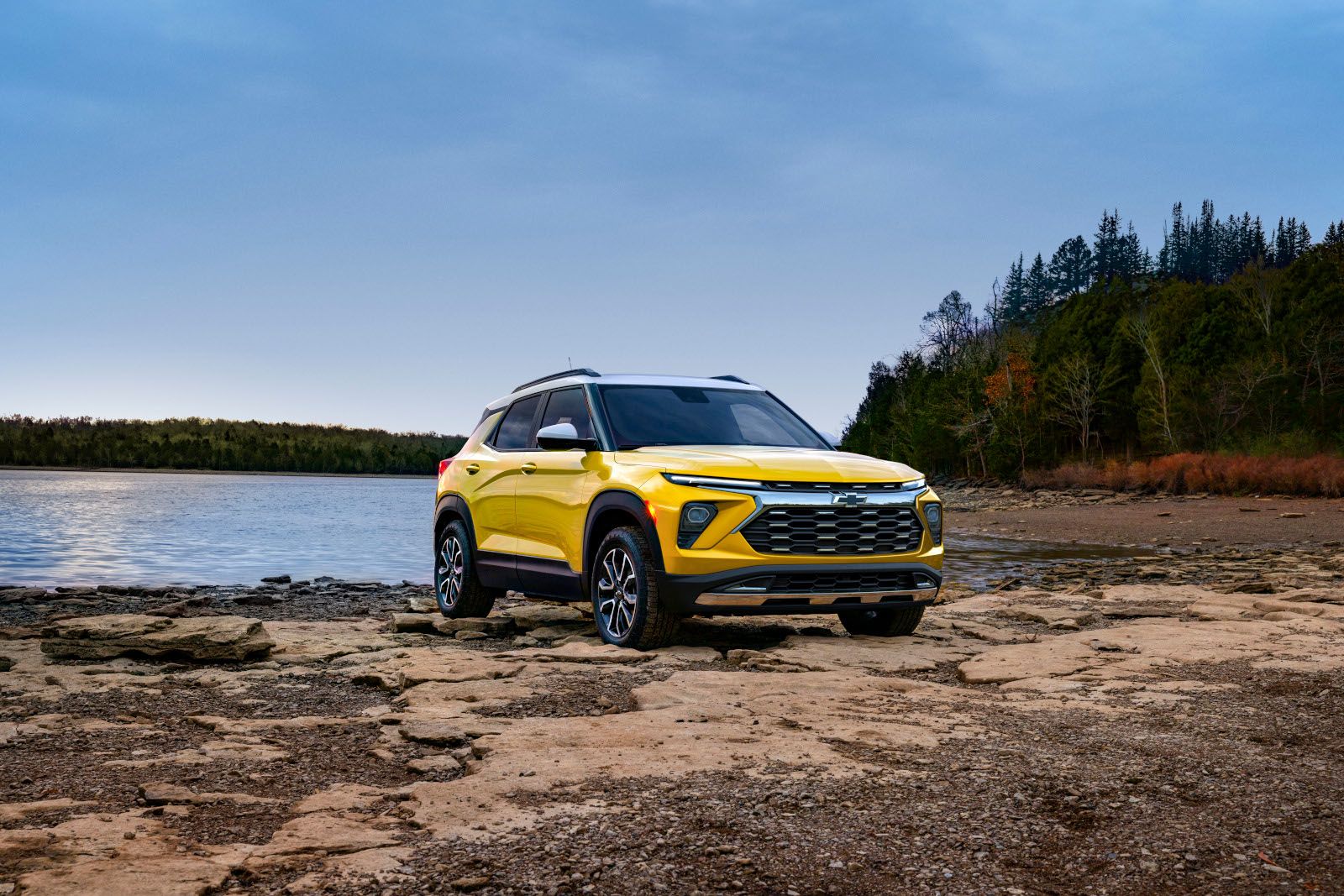 2026 Chevrolet Trailblazer - a yellow 2026 Chevrolet Trailblazer parked on a rocky shore by a lake - Humberview Group - New car dealerships in Ontario