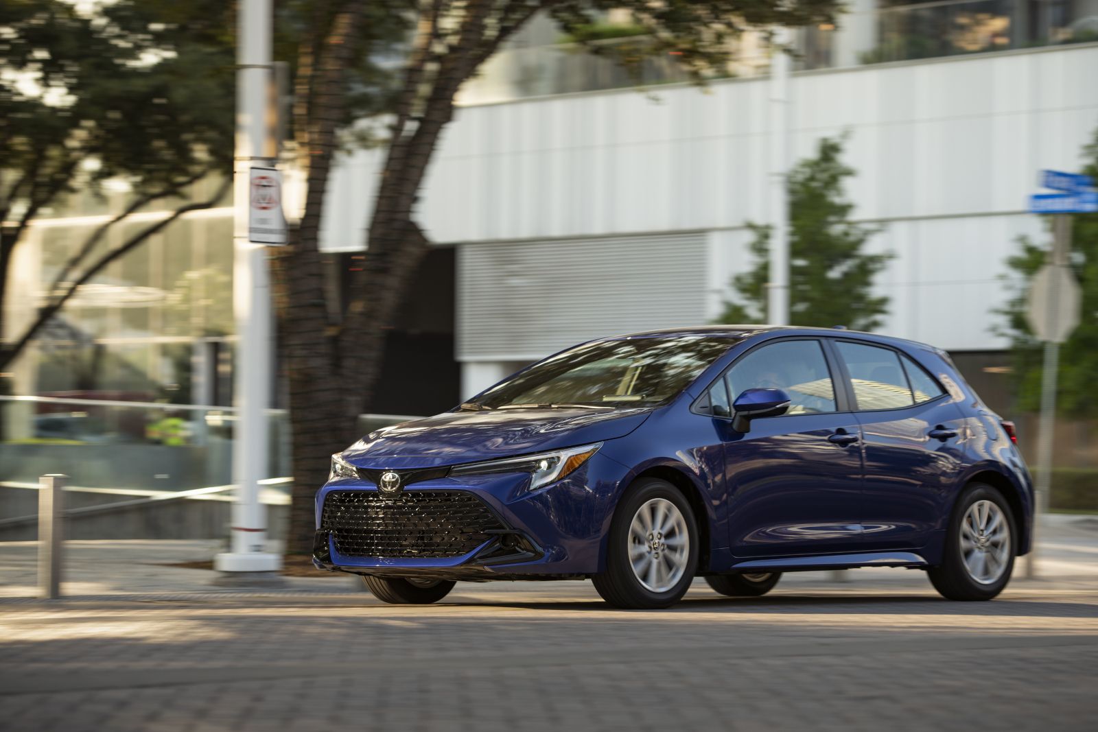 2027 Toyota Corolla - front three-quarter view of a blue 2027 Toyota Corolla hatchback driving on an urban road - Humberview Group - New car dealerships in Ontario
