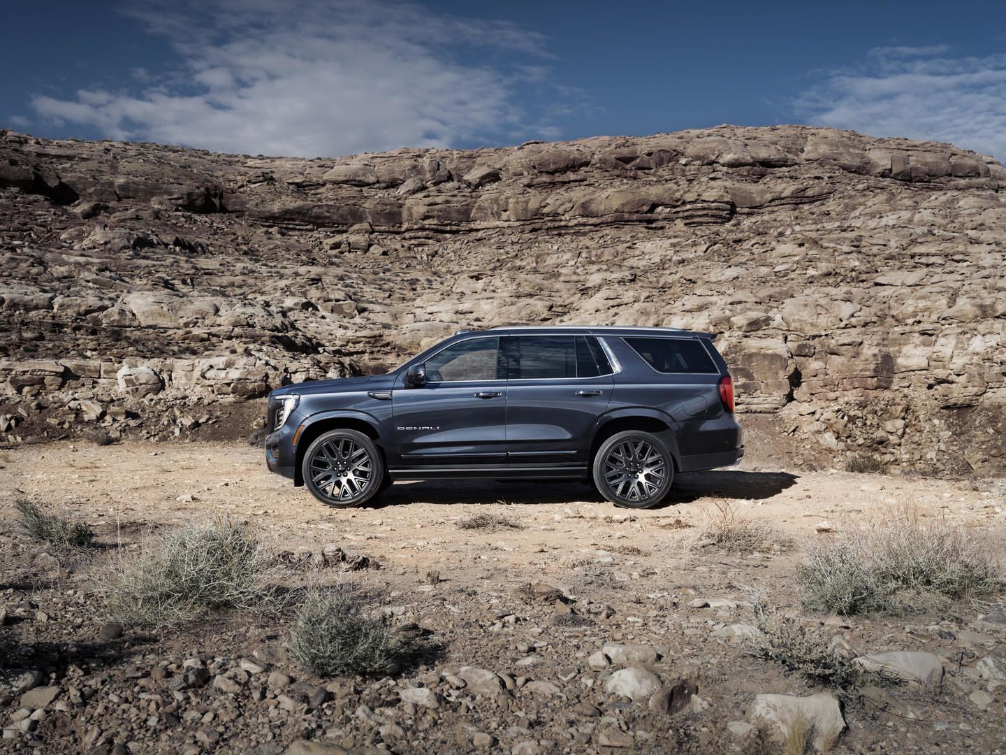 2026 GMC Yukon - profile view of a dark grey 2026 GMC Yukon Denali Ultimate parked against a rocky mountain backdrop - Humberview Group - New car dealerships in Ontario
