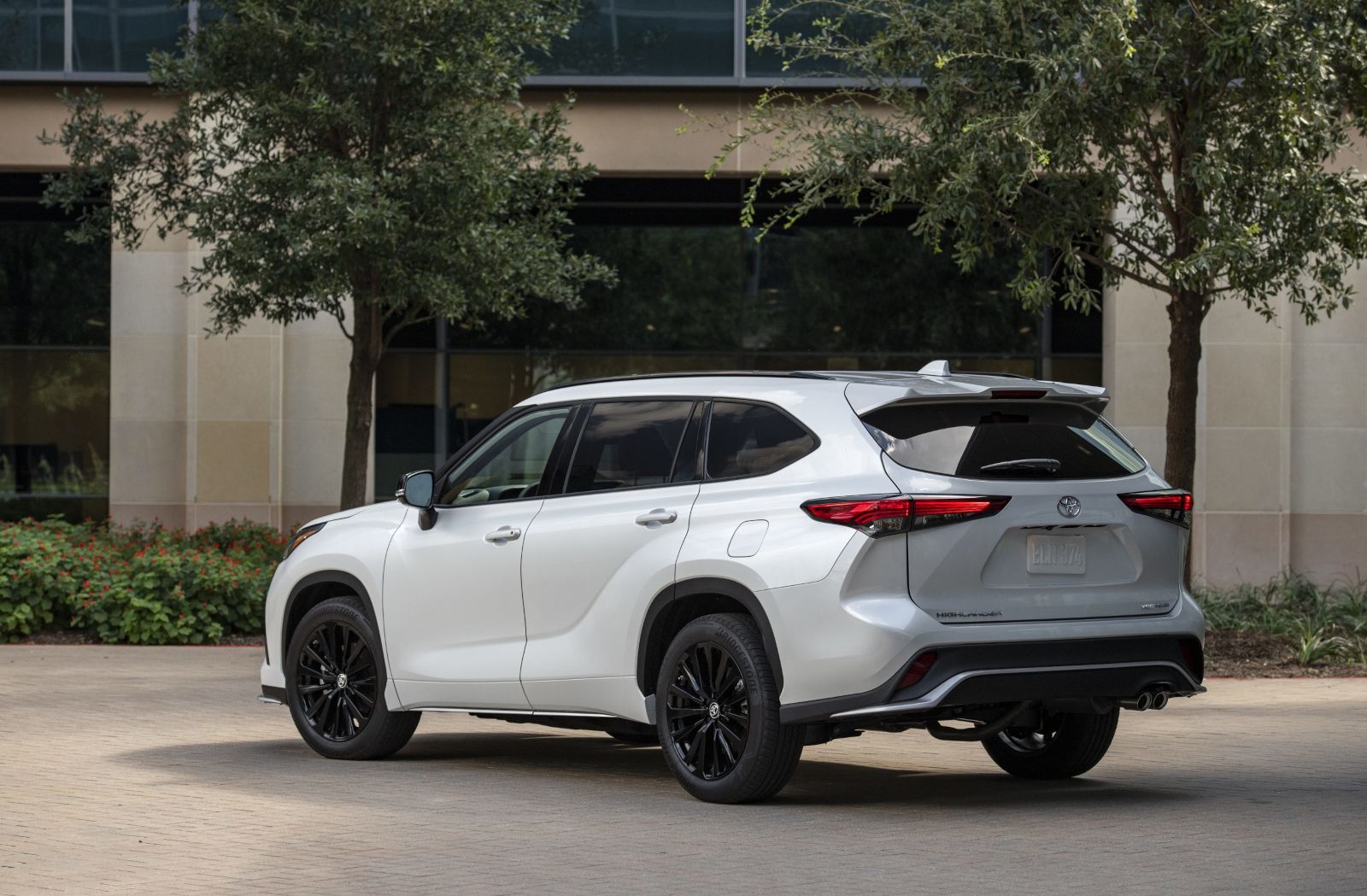 2026 Toyota Highlander - rear three-quarter view of a white 2026 Toyota Highlander parked outside an office building - Goderich Toyota - Toyota new car dealership in Goderich, Ontario