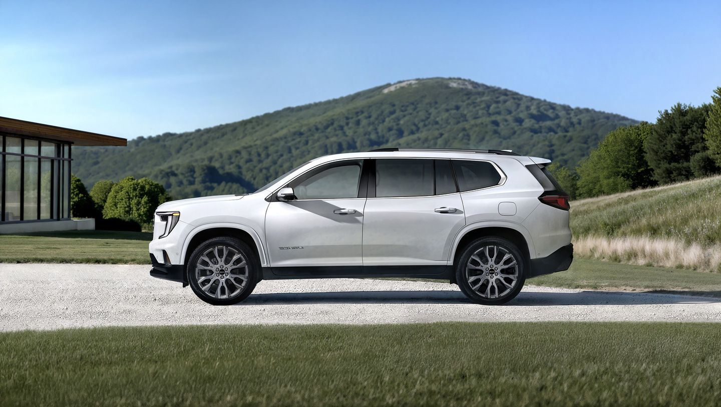 2026 GMC Acadia - side profile of a white 2026 GMC Acadia parked on a gravel drive with a mountain background - Applewood Chevrolet, Buick, GMC - GMC new car dealership in Mississauga, Ontario