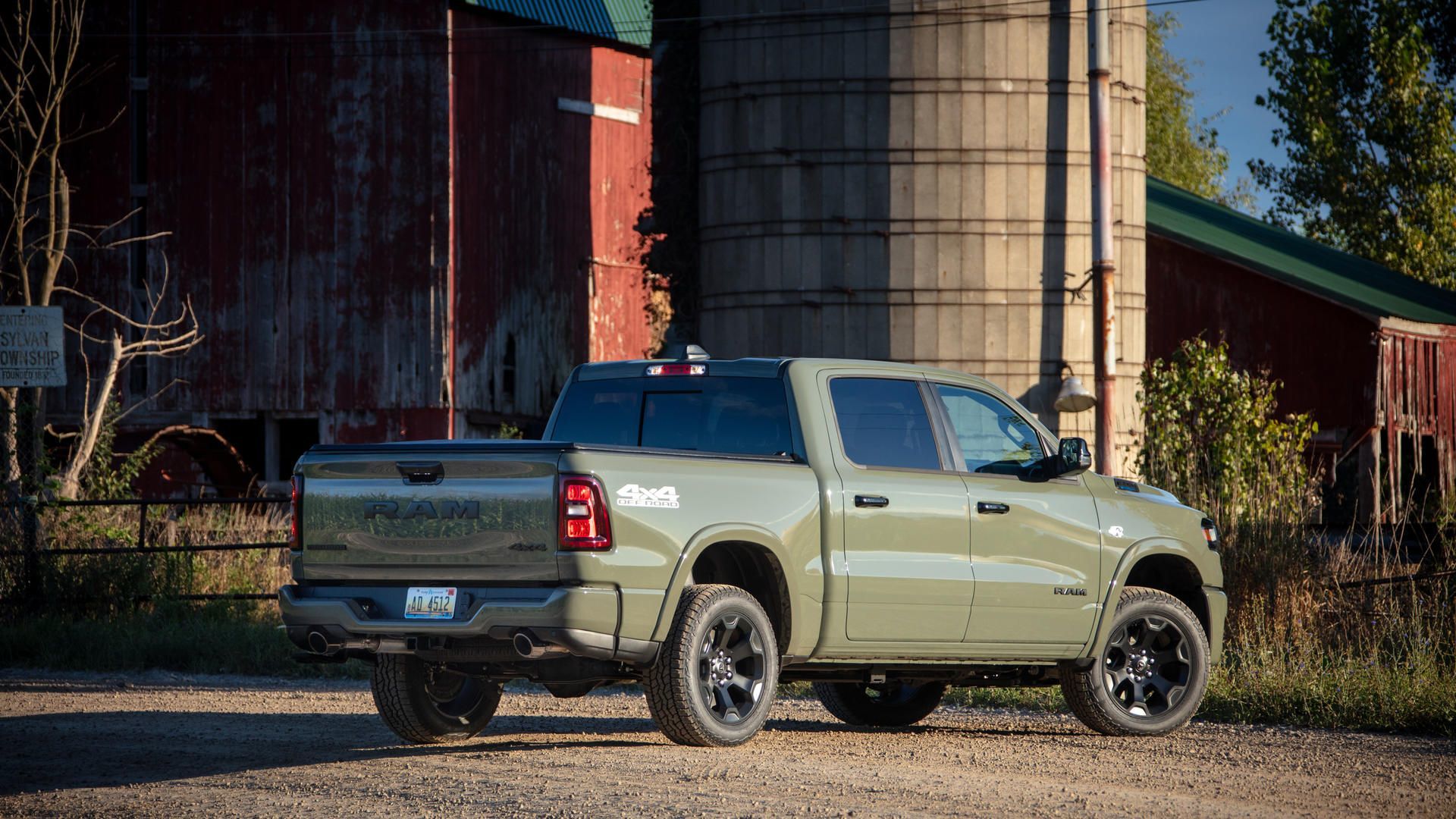 2027 Ram 1500 - Rear three-quarter view of an olive green Ram 1500 parked near a barn and silo - Cooksville Chrysler, Jeep, Dodge, Ram - Ram new car dealership in Mississauga, Ontario