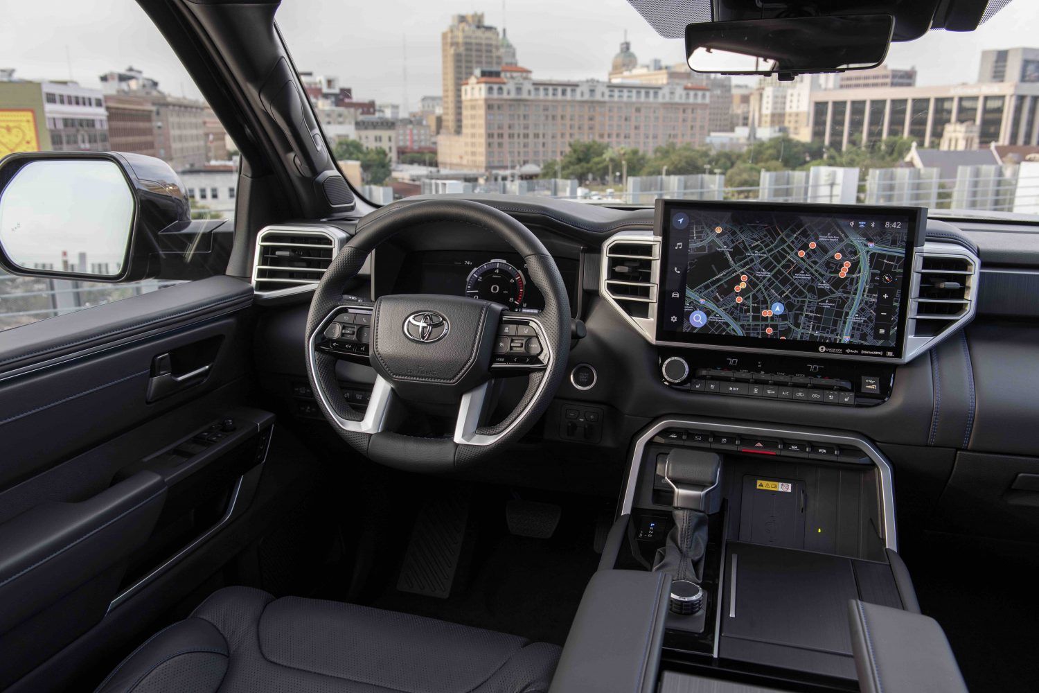 2027 Toyota Tundra - interior view of the 2027 Toyota Tundra driver's cockpit showing the dashboard and large infotainment screen with a city background - Goderich Toyota - Toyota new car dealership in Goderich, ON