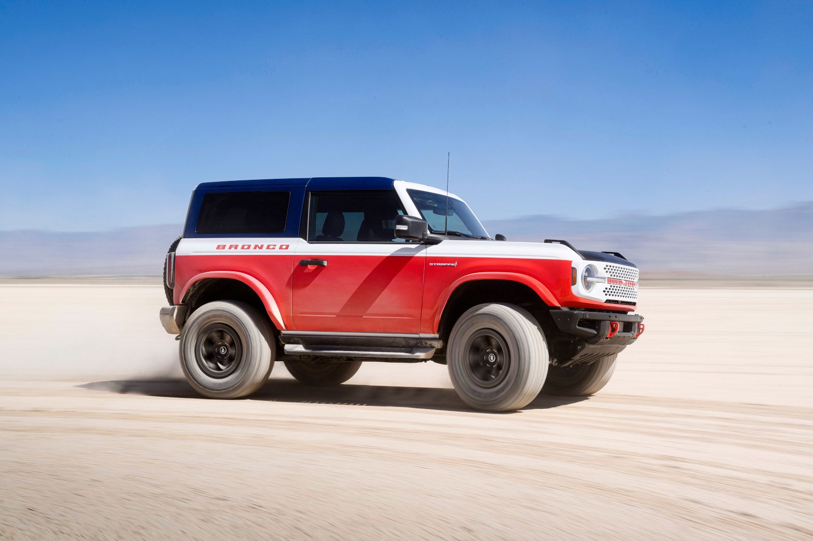 2027 Ford Bronco - a side view of a red, white, and blue 2027 Ford Bronco Heritage Limited Edition driving in a desert - Mayfield Ford - New car dealership in Brampton, Ontario