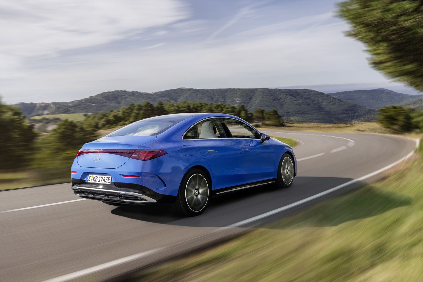 2027 Mercedes-Benz CLA - rear three-quarter view of a blue 2027 Mercedes-Benz CLA driving on a mountain road - Mercedes-Benz Brampton - Mercedes-Benz car dealership in Brampton, Ontario