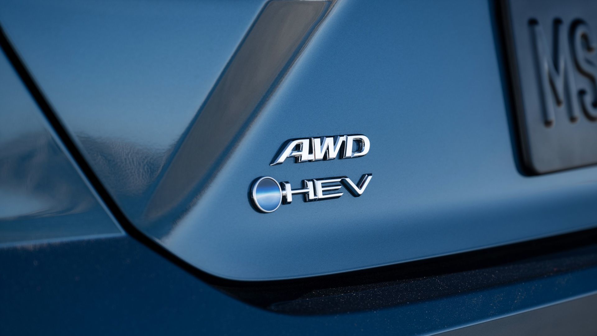 Toyota Camry - close-up view of the chrome "AWD" and "HEV" badges on the trunk of a blue Toyota Camry Hybrid - Oakville Toyota - Toyota car dealership in Oakville, Ontario