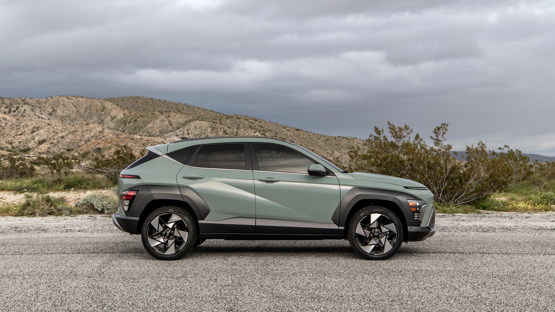 2027 Hyundai Kona - side profile view of a sage green 2027 Hyundai Kona parked on a rural roadside - Woodstock Hyundai - Hyundai new car dealership in Woodstock, Ontario