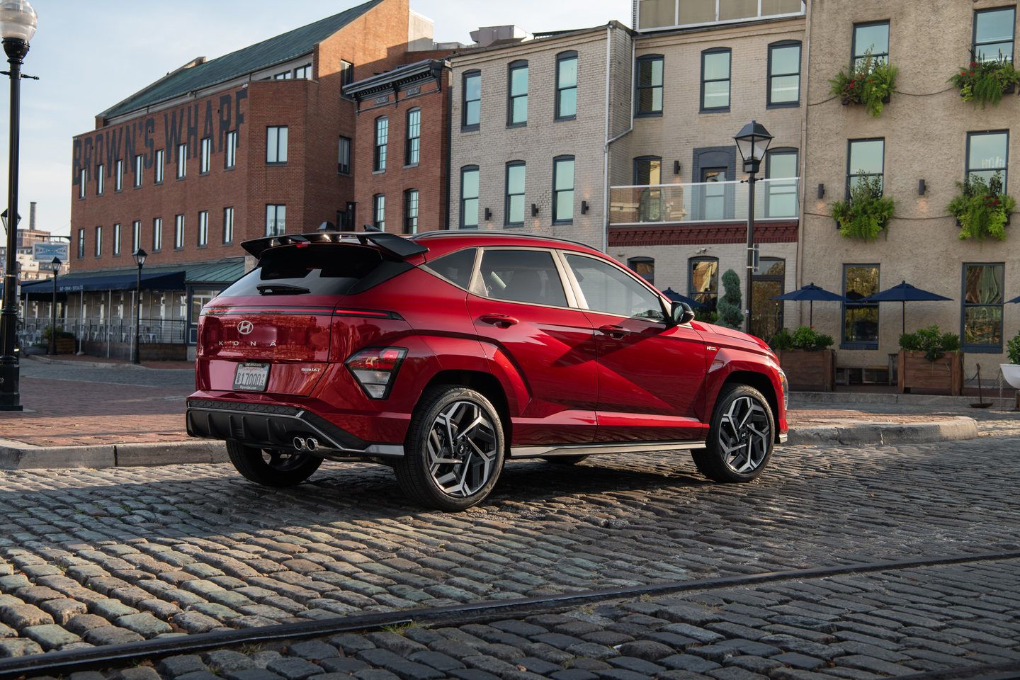 2027 Hyundai Kona N Line - rear three-quarter view of a red 2027 Hyundai Kona N Line parked on a cobblestone street - Woodstock Hyundai - Hyundai new car dealership in Woodstock, Ontario