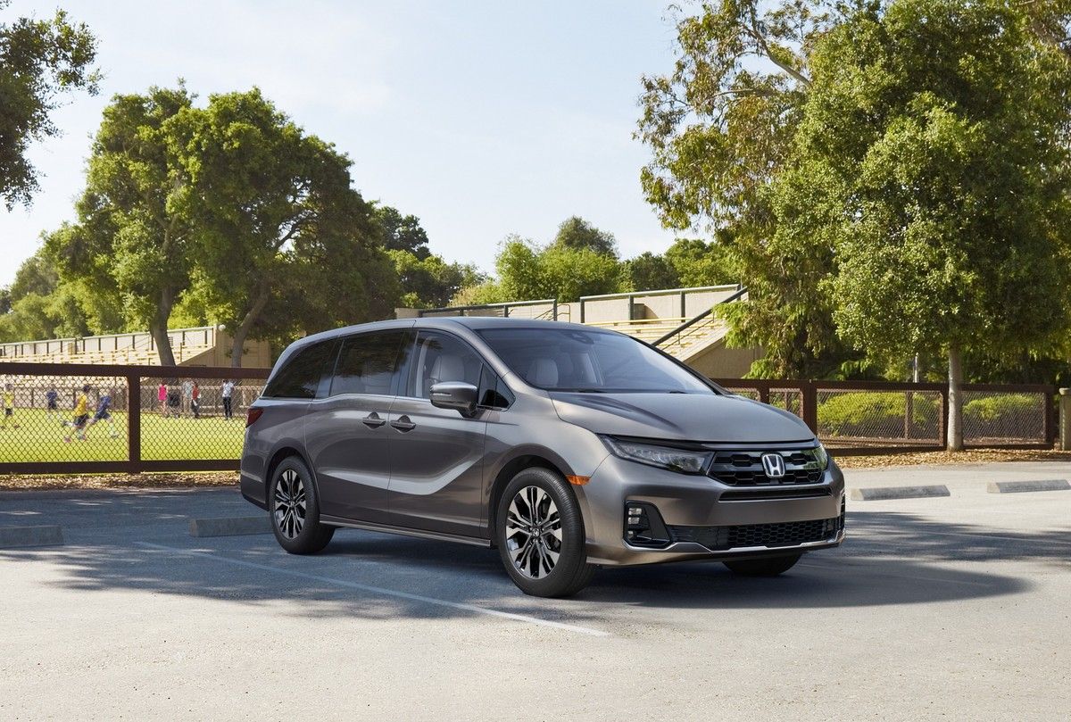 2027 Honda Odyssey - front three-quarter view of a grey 2027 Honda Odyssey parked in a paved lot near a sports field - Humberview Group - New car dealerships in Ontario