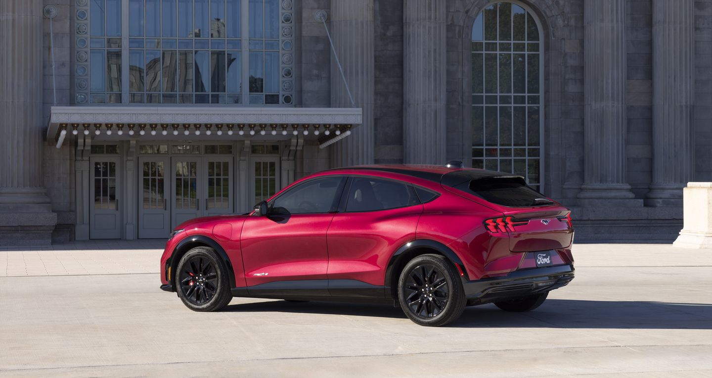 2027 Ford Mustang Mach-E - rear three-quarter view of a red 2027 Ford Mustang Mach-E parked outside a stone building - Humberview Group - New car dealerships in Ontario