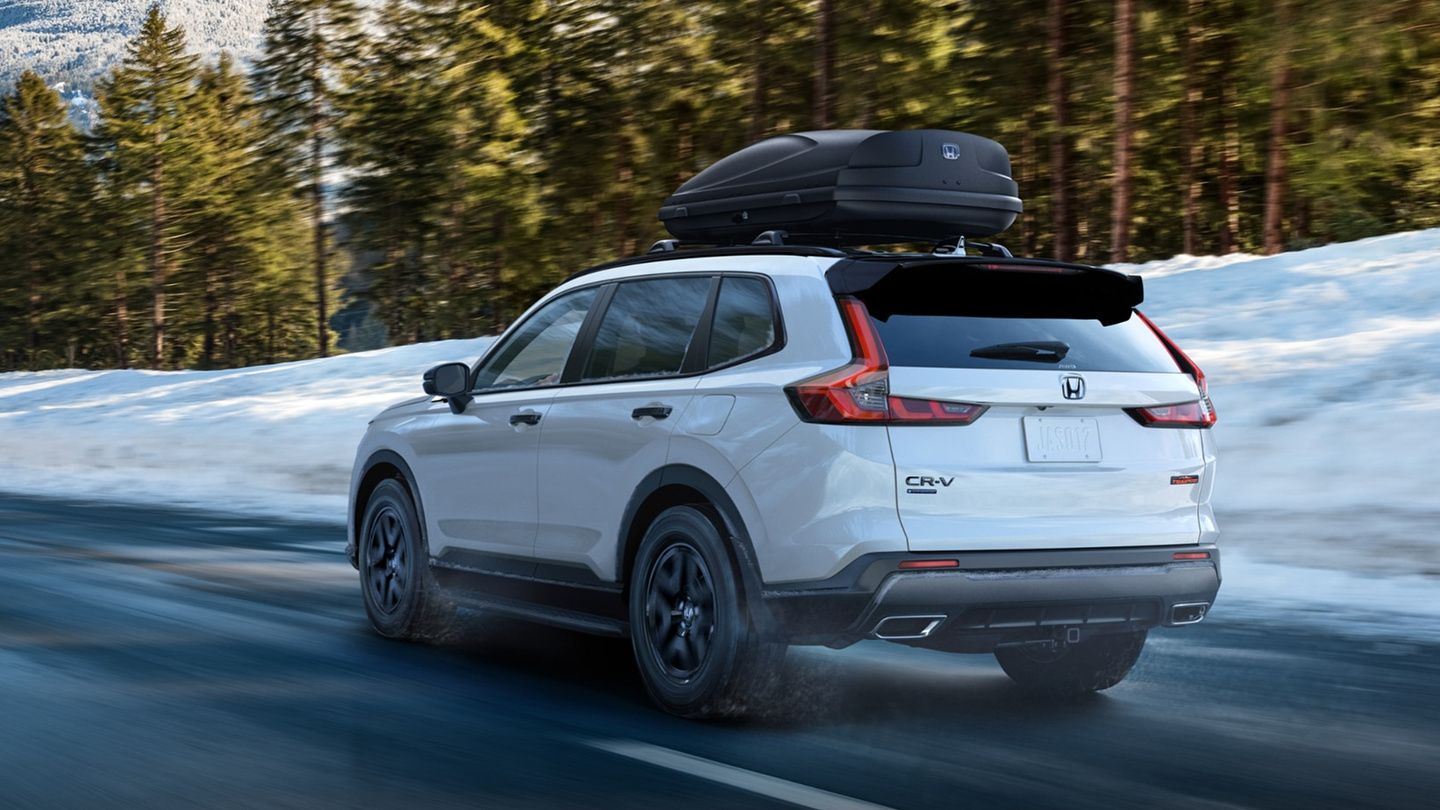 2027 Honda CR-V - rear three-quarter view of a white 2027 Honda CR-V with a roof cargo box driving on a snow-lined road - Humberview Group - New car dealerships in Ontario