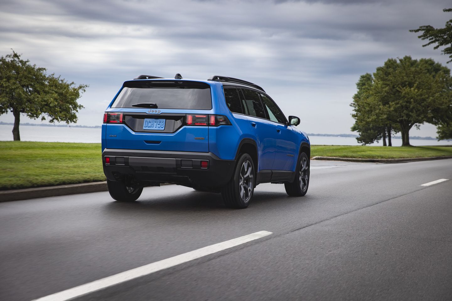 2027 Jeep Cherokee - rear view of a blue 2027 Jeep Cherokee driving along a coastal road - Cooksville Chrysler, Jeep, Dodge, Ram - Jeep car dealership in Mississauga, Ontario