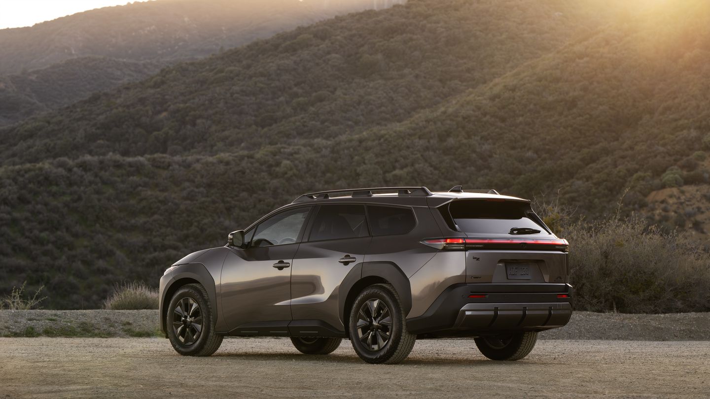 2027 Toyota bZ Woodland - rear three-quarter view of a bronze 2027 Toyota bZ Woodland parked on a dirt road with mountain backdrop - Orangeville Toyota - Toyota new car dealership in Orangeville, Ontario