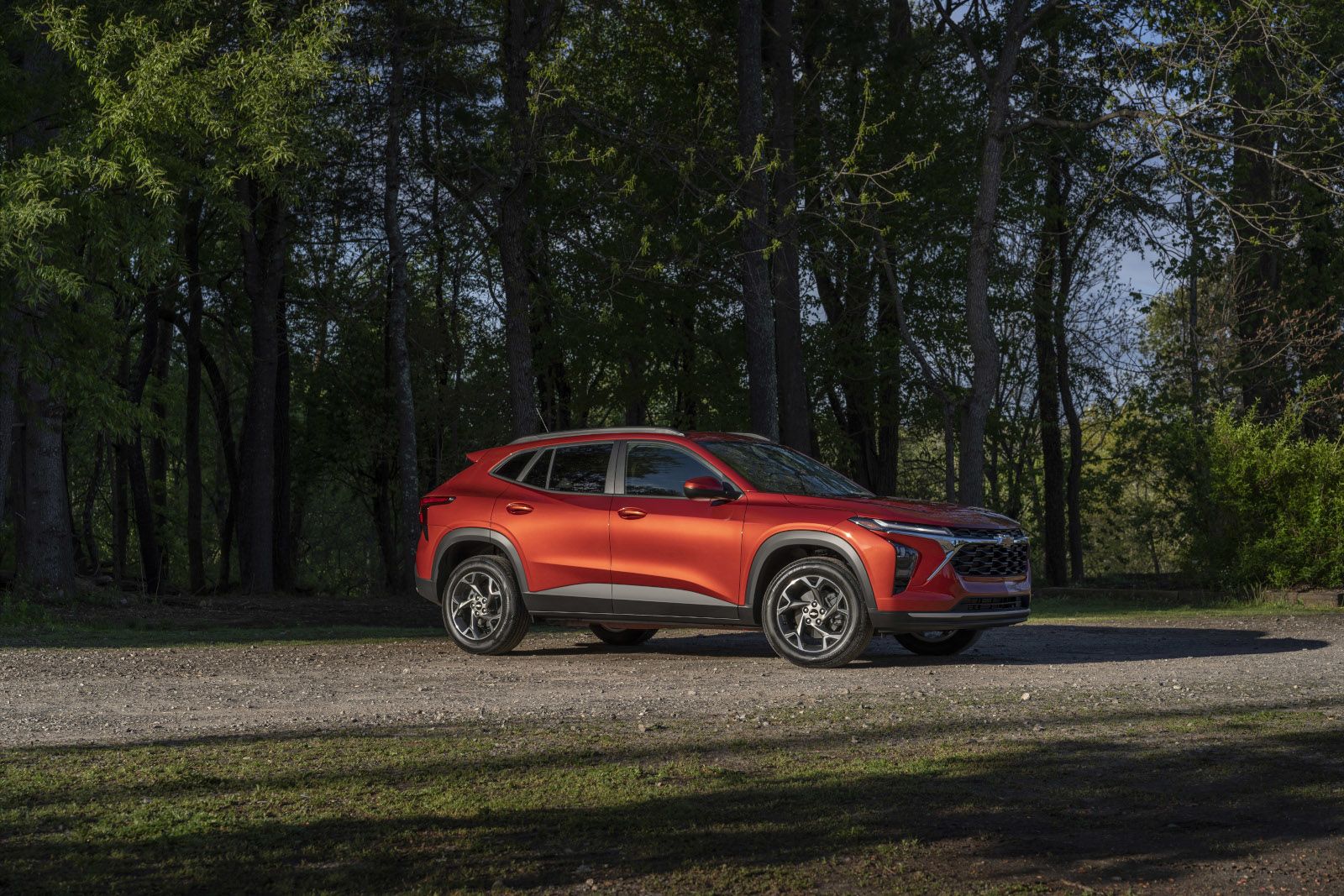 2027 Chevrolet Trax - a side view of an orange 2027 Chevrolet Trax on a gravel road in a wooded area - Applewood Chevrolet, Buick, GMC - Chevrolet car dealership in Mississauga, Ontario