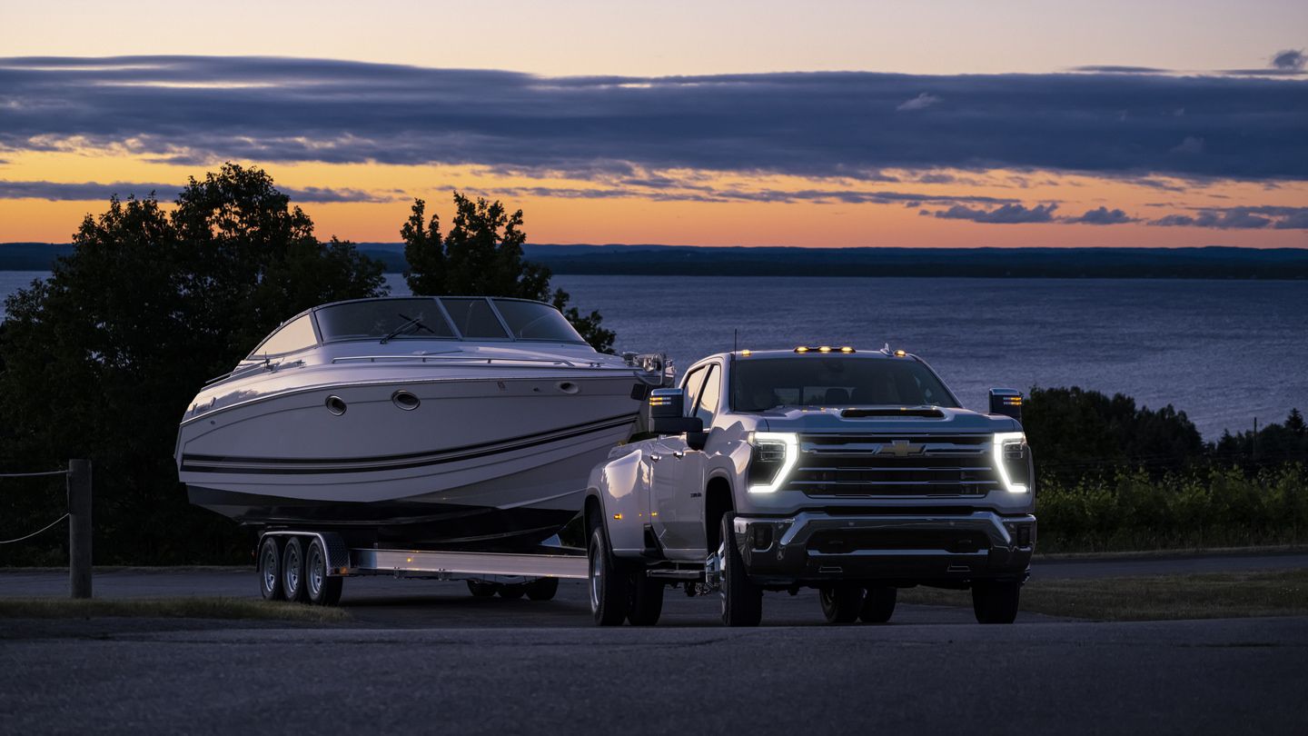 2027 Chevrolet Silverado 3500 HD - a white 2027 Chevrolet Silverado 3500 HD towing a boat at sunset - Humberview Chevrolet, Buick, GMC - Chevrolet car dealership in Toronto, Ontario
