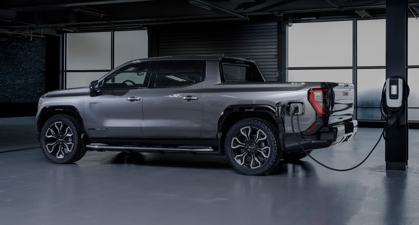 2027 GMC Sierra EV - side profile of a grey 2027 GMC Sierra EV plugged into an electric vehicle charger - Humberview Chevrolet, Buick, GMC - GMC car dealership in Toronto, Ontario