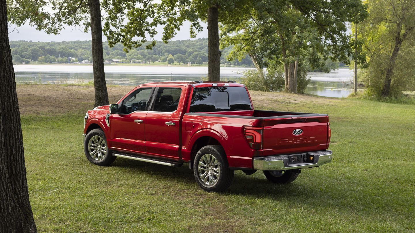 2027 Ford F-150 - rear three-quarter view of a red 2027 Ford F-150 parked in a grassy park near a lake - Bayfield Ford - Ford new car dealership in Barrie, Ontario