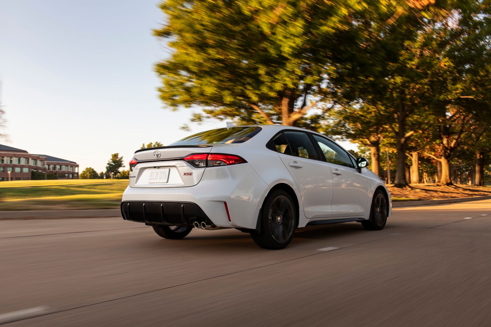 2027 Toyota Corolla - rear three-quarter view of a white Toyota Corolla XSE driving on a tree-lined road - Oakville Toyota - Toyota new car dealership in Oakville, Ontario