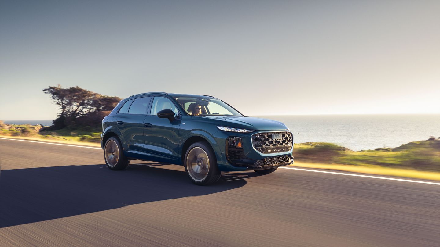 2027 Audi Q3 - front three-quarter view of a teal 2027 Audi Q3 driving along a coastal highway at sunset - Humberview Group - New car dealerships in Ontario