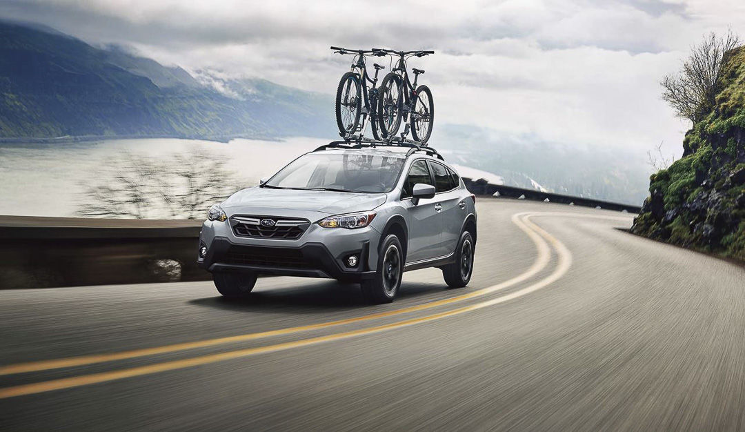 vue trois quart avant du Subaru Crosstrek 2022 roulant sur une route proche d'une étendue d'eau