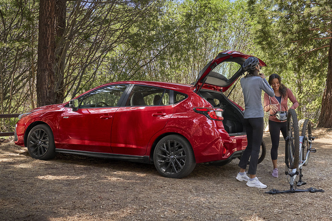 Vue arrière du Subaru Impreza 2024 avec valise ouverte et un couple partant faire du vélo