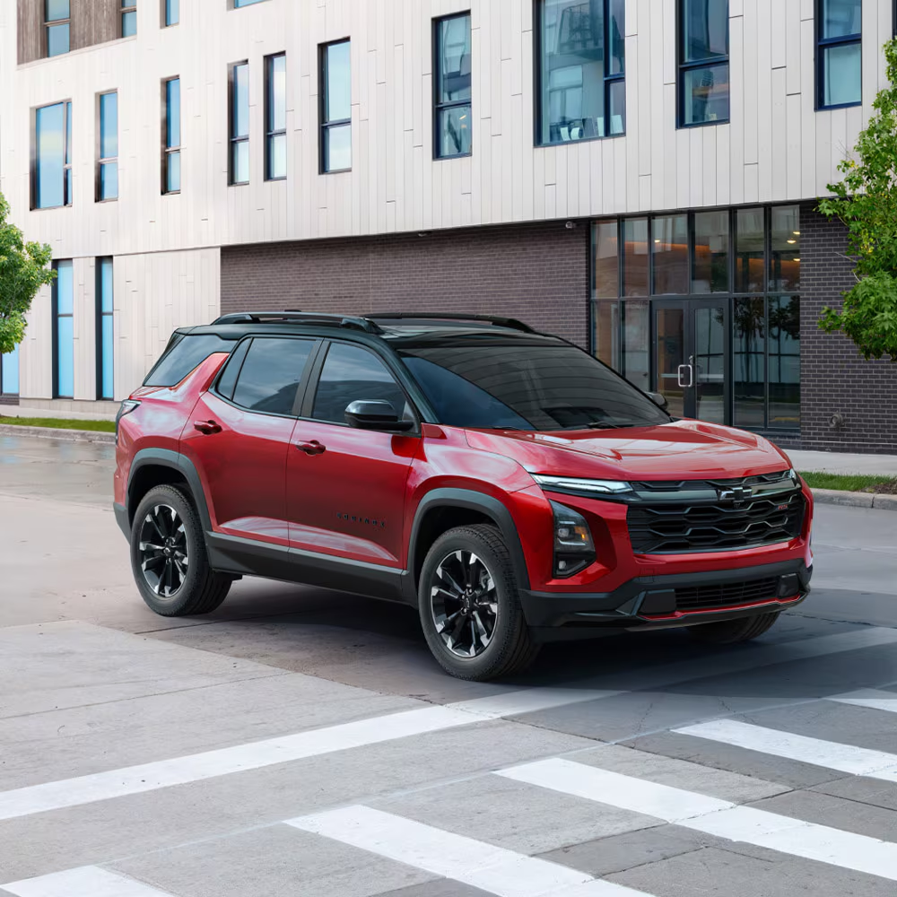 SUV rouge Chevrolet, avec un capot musclé et une calandre noire, stationné devant un bâtiment.