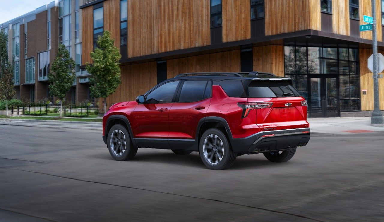 SUV rouge Chevrolet, montrant le hayon avec le logo Chevrolet, stationné devant un bâtiment moderne.