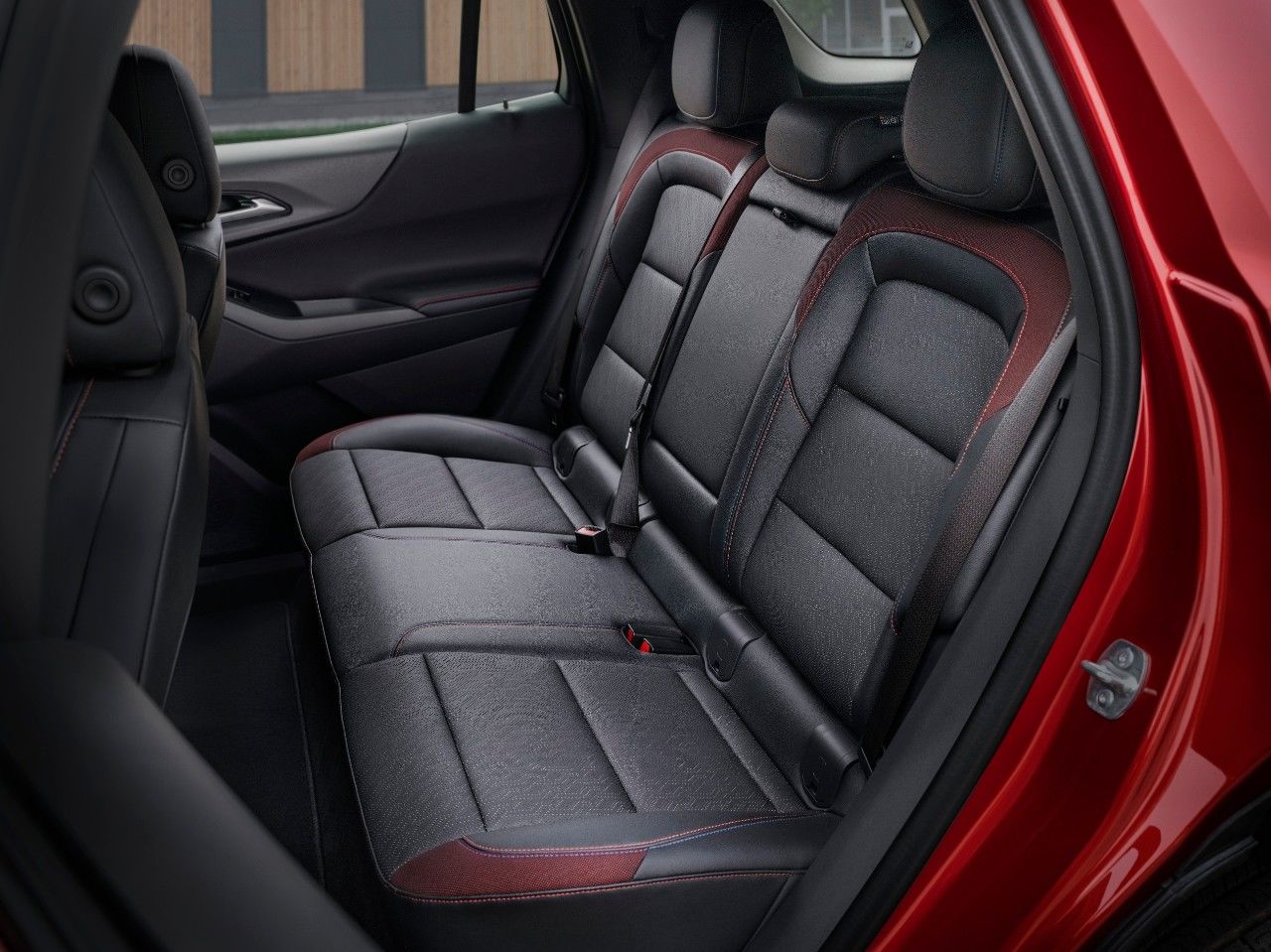 Close-up of the interior of a red car, highlighting the seat with contrasting red stitching.