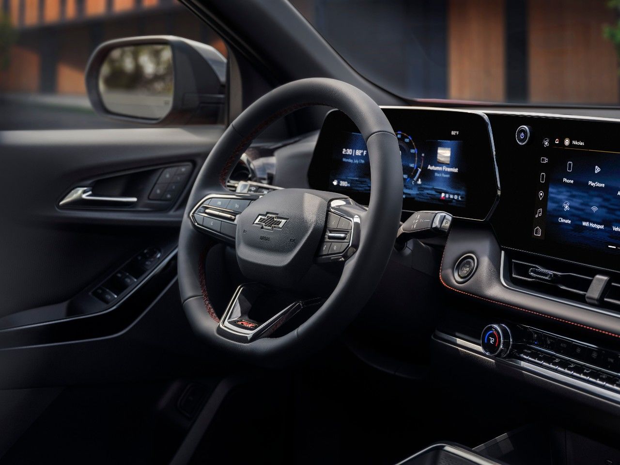 Close-up of a gear shift in a vehicle, with a display screen showing a song and navigation icons on the right side.