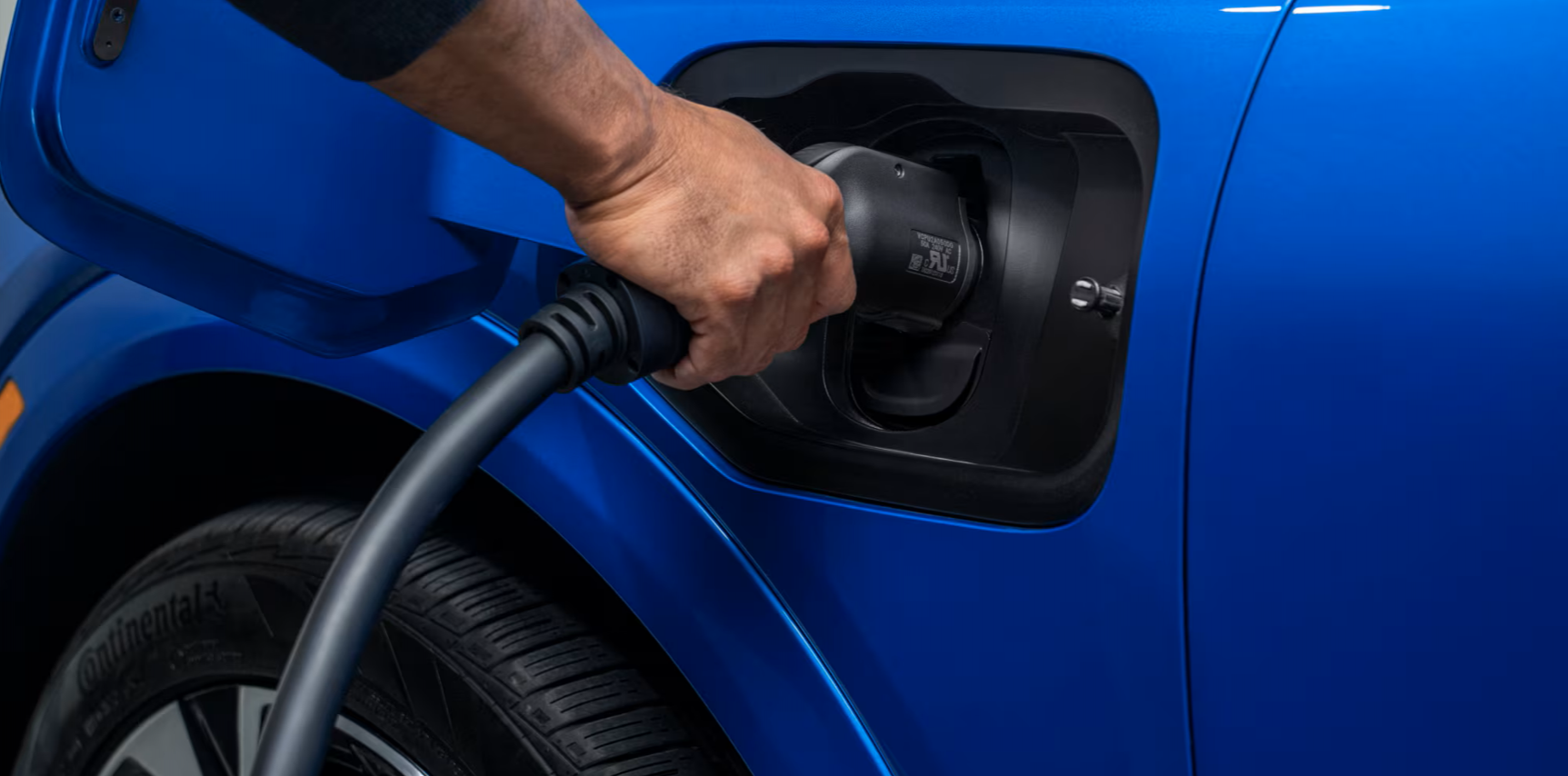 Hand plugging the 2025 Chevrolet Equinox EV into an electric charging station.