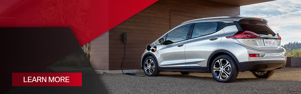 Learn more: image of a chevrolet bolt ev parked in front of a house charging at an electric station
