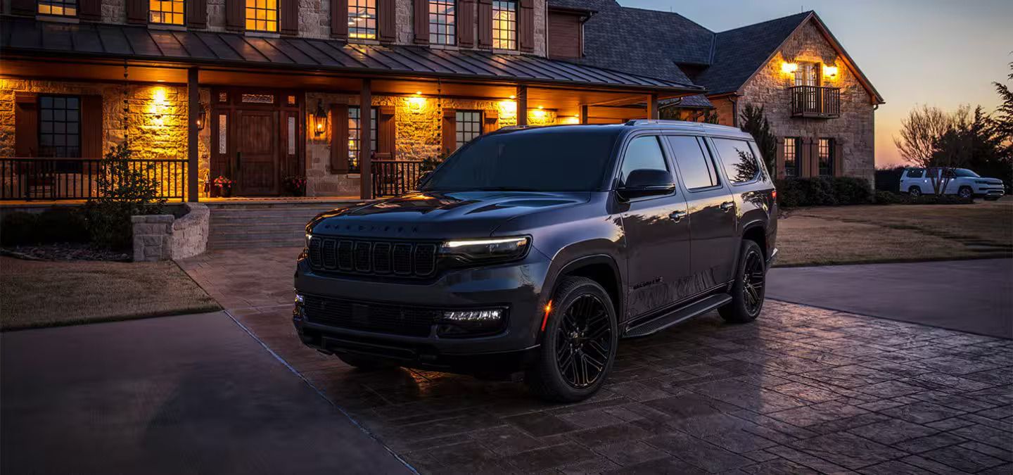 Side frontal view of a 2026 Jeep Wagoneer in front of a house at sunset