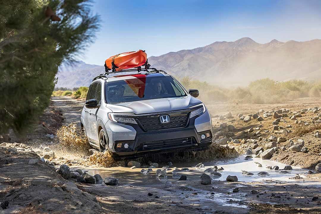 front view of a Honda Passport on a muddy, rocky road