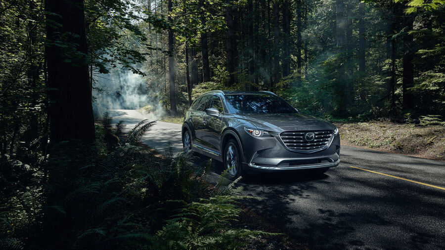 Frontal side view of a Mazda CX-9 on a forest road