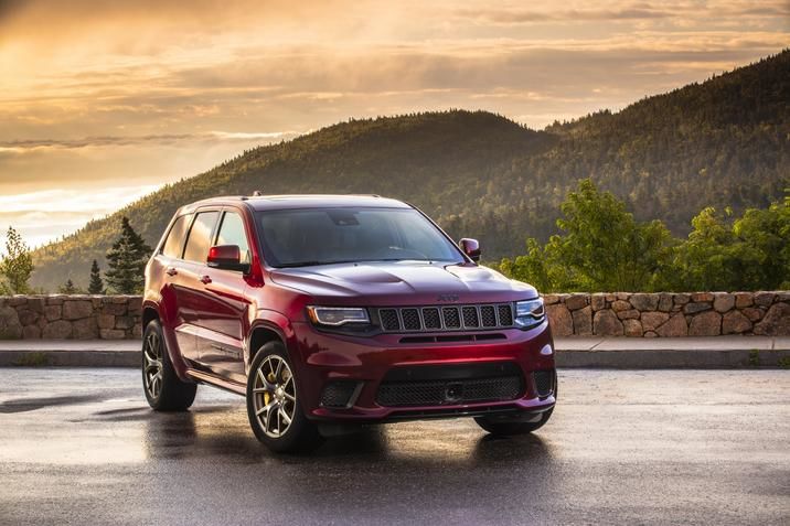 Frontal side view of a Jeep Grand Cherokee with a mountain in the background during sunset