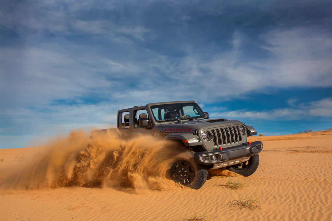 vue latérale d'un Jeep Wrangler 2022 sur des dunes de sable