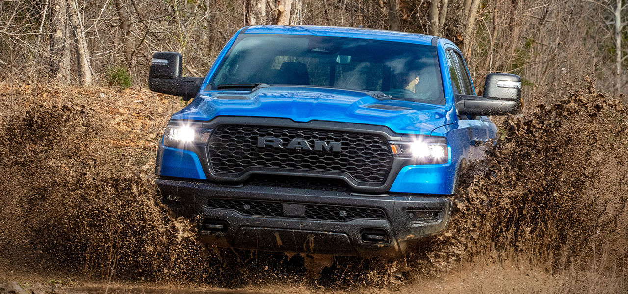 Front view of RAM 1500 2025, crossing a mud puddle at full power