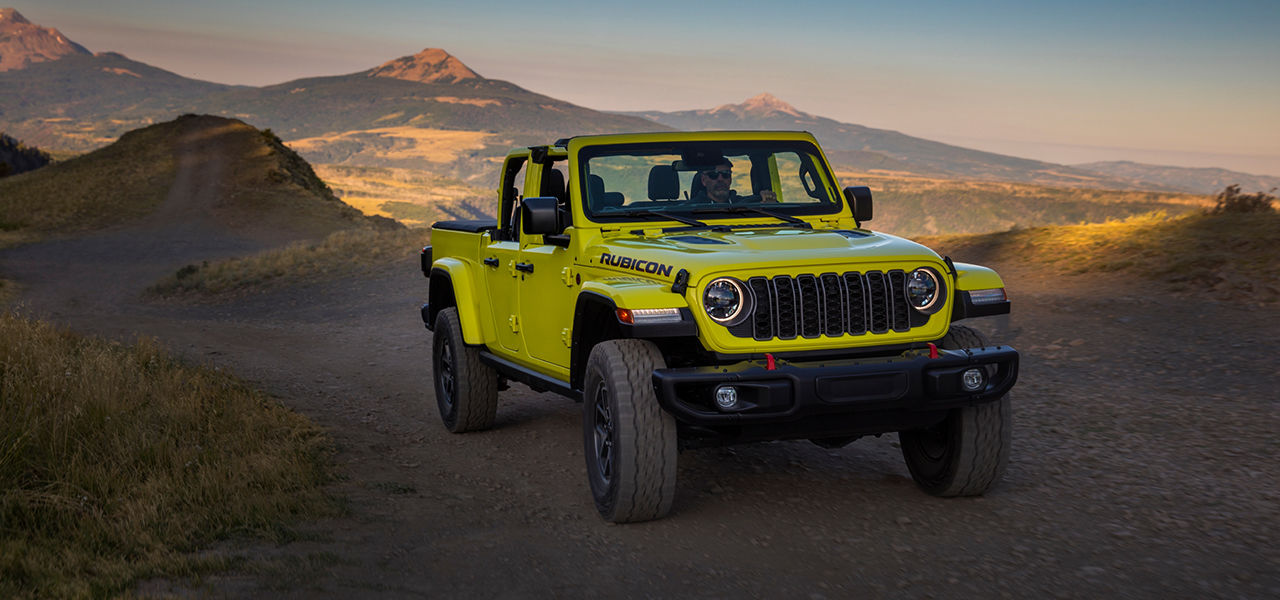 3/4 front and side view of Jeep Gladiator Rubicon on sandy road with sunset