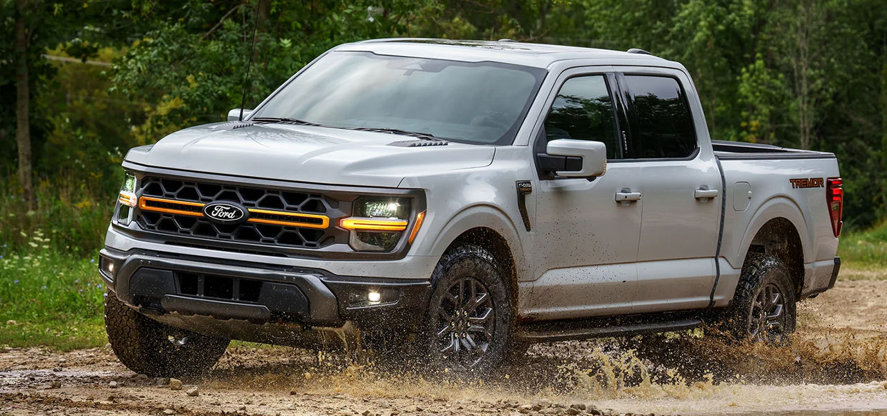 3/4 front and side view of Ford F-150 2024 crossing a mud puddle