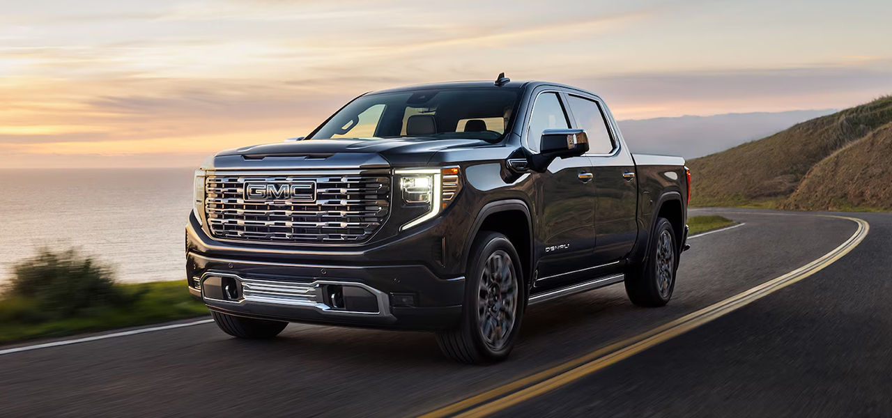 3/4 front and side view of GMC Sierra 2024 on full power road with sunset