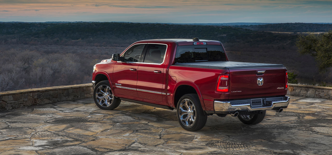 Rear view of Ram 2024 on paved rest area and view of wooded horizon