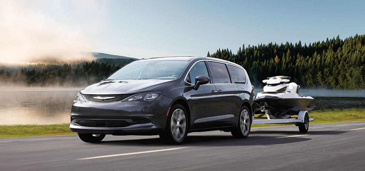 3/4 front and side view of the Chrysler Grand Caravan 2024 on the road with trailer and watercraft at full power