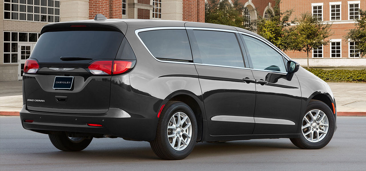 Rear view of Chrysler Grand Caravan 2024, parked in front of a school