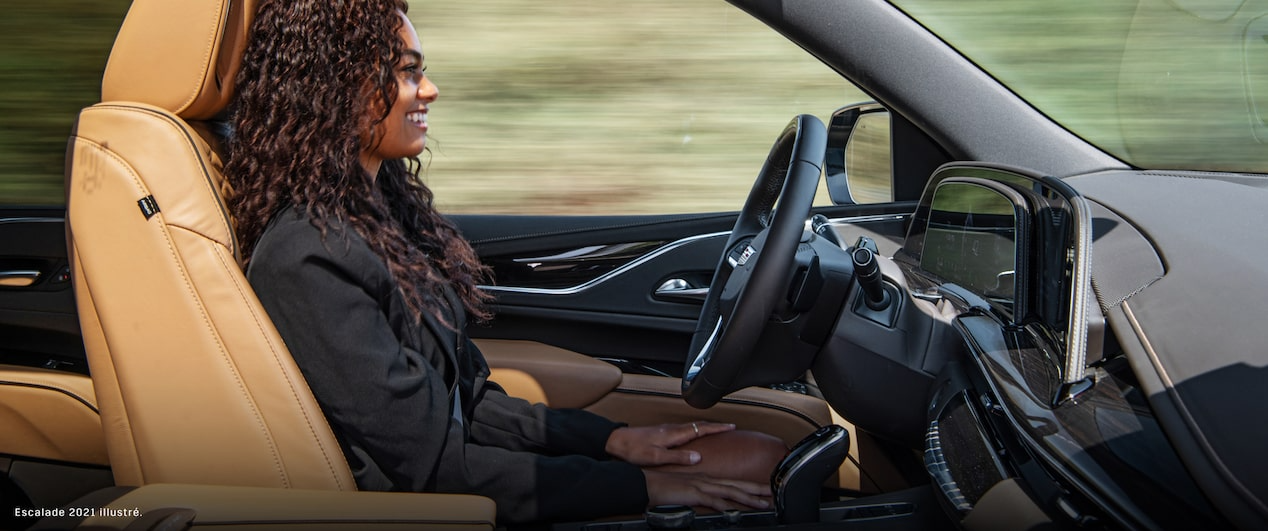 Une femme assise dans son Cadillac utilisant le service Super Cruise a les mains sur les cuisses pendant que le véhicule se conduit de lui-même