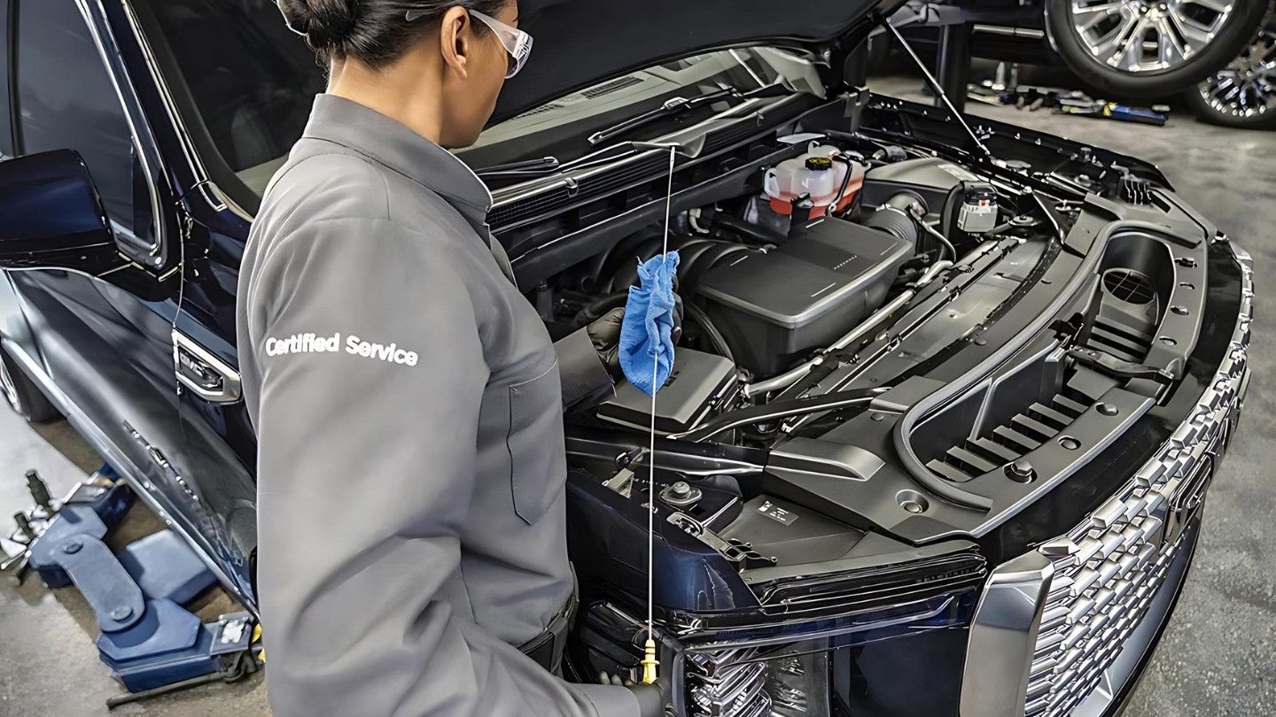 GM technician checking engine oil in a service bay for walk-in oil change service in Laval.