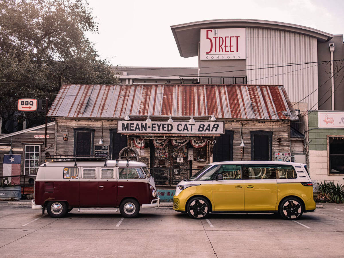 two VW Westfalia from different eras face to face in front of an old restaurant